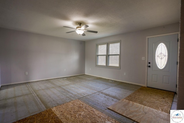 foyer with a textured ceiling, a ceiling fan, and baseboards