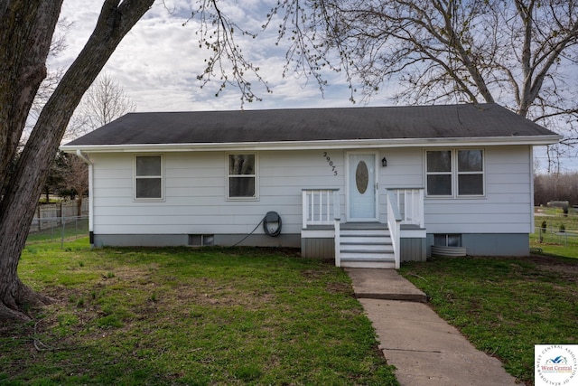 view of front facade featuring fence, a shingled roof, and a front yard