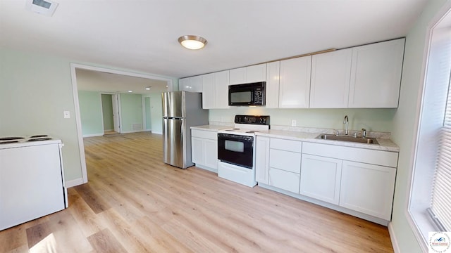 400 E 12th St, Sedalia, MO 65301 - kitchen featuring electric stove, freestanding refrigerator, black microwave, a sink, and light wood-style floors
