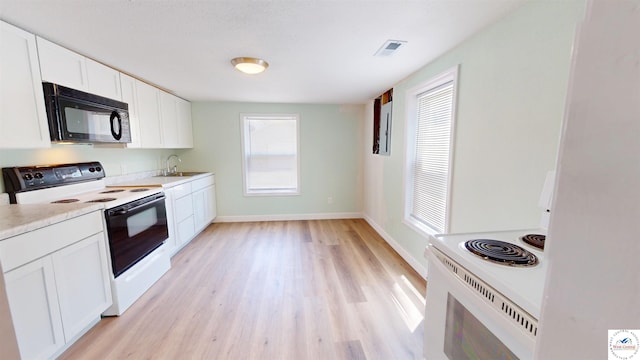 400 E 12th St, Sedalia, MO 65301 - kitchen with electric range, black microwave, a sink, light wood finished floors, and white cabinetry