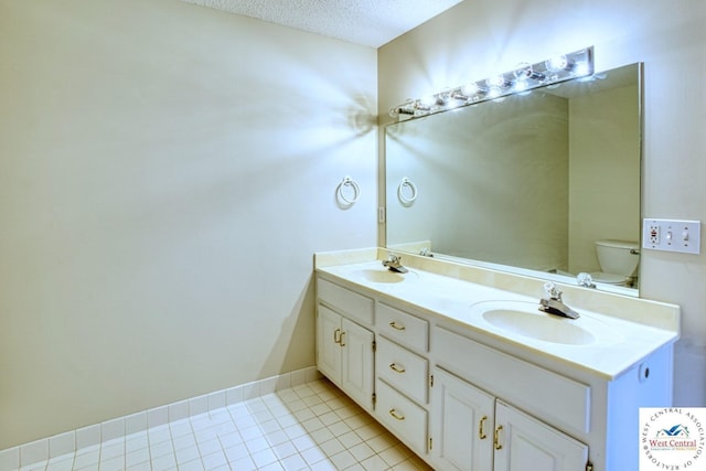 bathroom with toilet, a textured ceiling, double vanity, and a sink