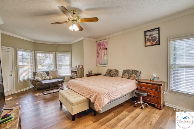 bedroom with a textured ceiling, wood finished floors, ornamental molding, and baseboards