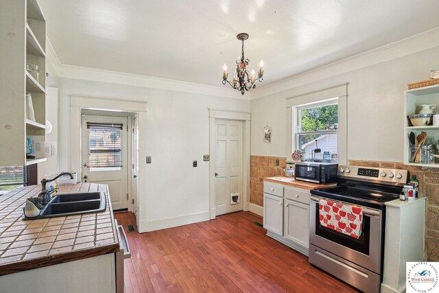 309 E Gay St, Warrensburg, MO 64093 - kitchen featuring stainless steel range with electric stovetop, tile counters, open shelves, a chandelier, and crown molding