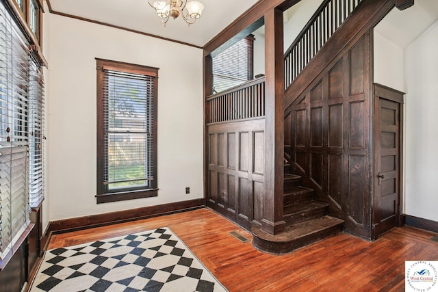 309 E Gay St, Warrensburg, MO 64093 - entrance foyer with wood finished floors, a chandelier, stairs, and crown molding