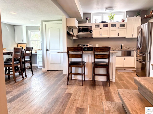 kitchen featuring a kitchen bar, a sink, stainless steel appliances, and light wood-type flooring