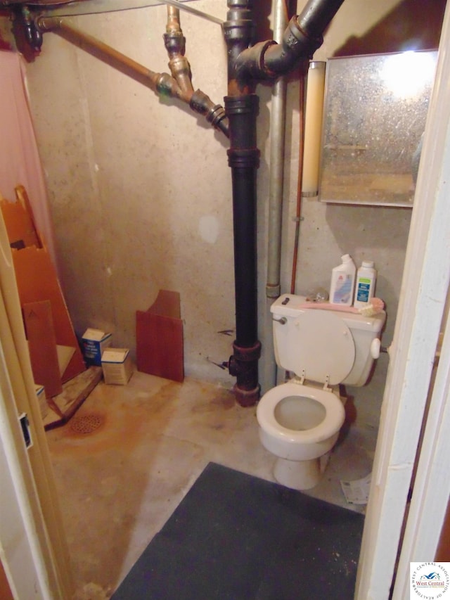 bathroom with toilet and concrete flooring