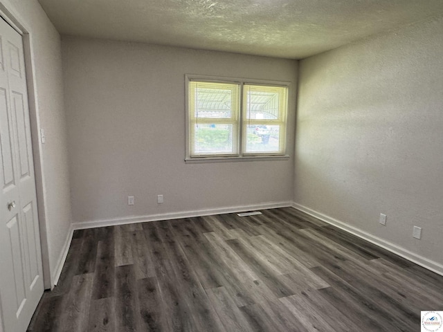 1404 S Grand Ave, Sedalia, MO 65301 - unfurnished bedroom with baseboards, dark wood-style flooring, a textured ceiling, and visible vents