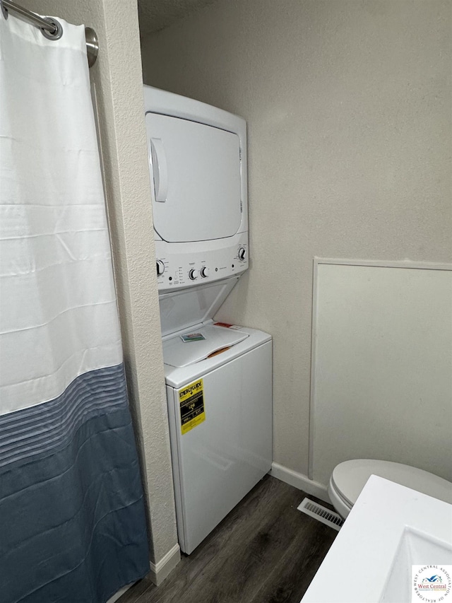 1404 S Grand Ave, Sedalia, MO 65301 - laundry area featuring laundry area, dark wood-style flooring, visible vents, stacked washer / drying machine, and baseboards
