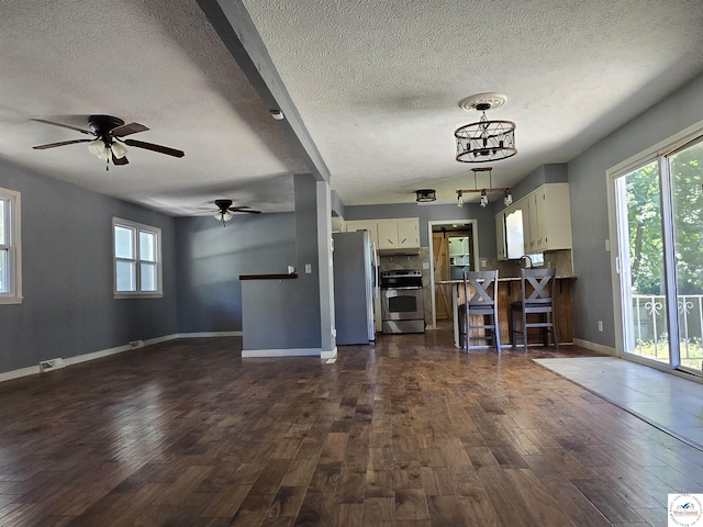 kitchen featuring a textured ceiling, open floor plan, stainless steel appliances, and dark wood finished floors