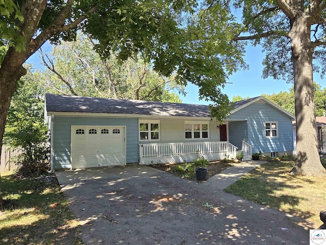 ranch-style home featuring covered porch, aphalt driveway, and an attached garage