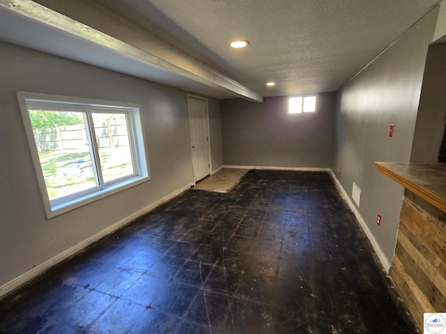 below grade area with baseboards, recessed lighting, and a textured ceiling