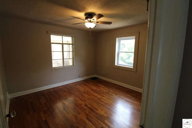 empty room with baseboards, ceiling fan, a textured ceiling, and dark wood-type flooring