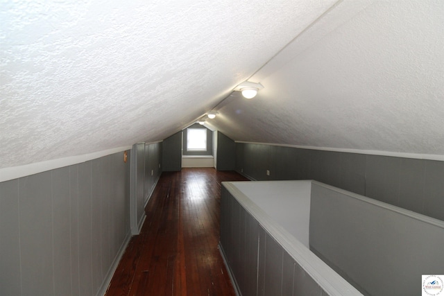 bonus room featuring a textured ceiling, dark wood-style flooring, and lofted ceiling