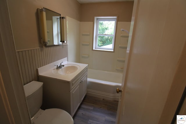 full bathroom with wood finished floors, wainscoting, bathing tub / shower combination, toilet, and vanity