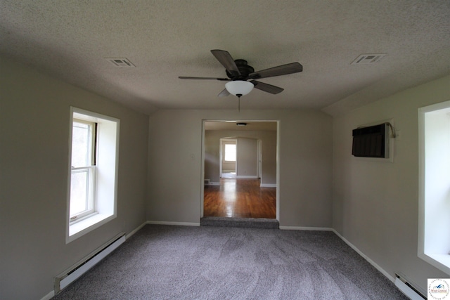 empty room with baseboard heating, ceiling fan, carpet flooring, visible vents, and a textured ceiling