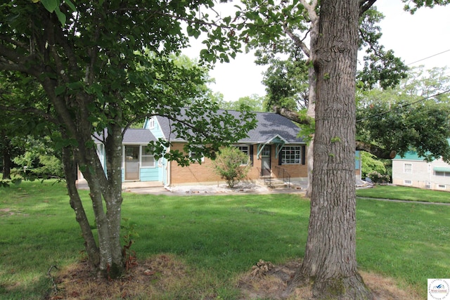 view of front facade with a front lawn, a shingled roof, and brick siding