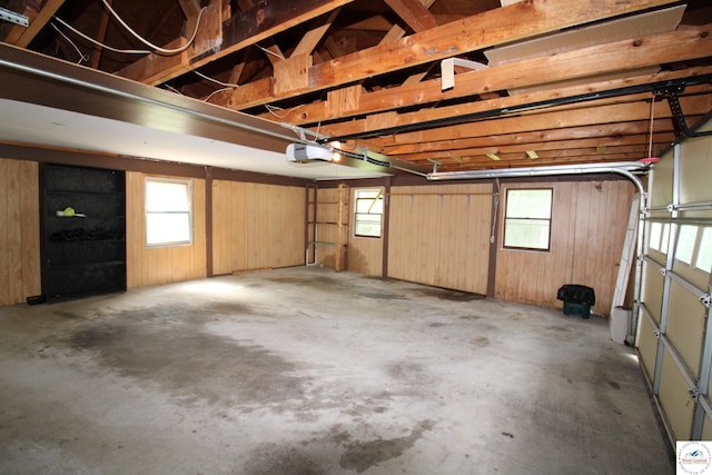 garage featuring a garage door opener and wooden walls