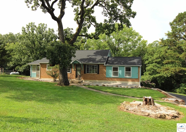 view of front of property with a front lawn, a shingled roof, entry steps, and brick siding