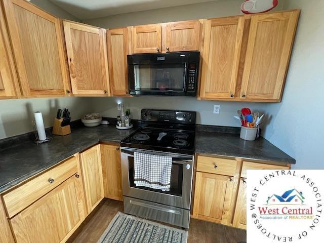 412 E Walnut St, Clinton, MO 64735 - kitchen featuring black microwave, stainless steel electric range, dark countertops, and light brown cabinetry