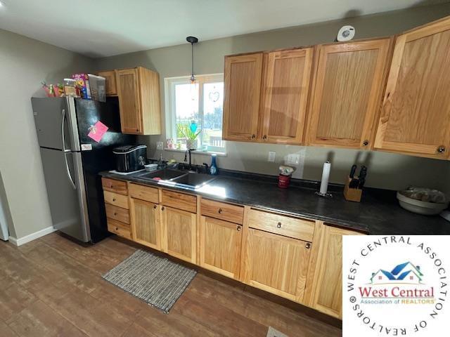 412 E Walnut St, Clinton, MO 64735 - kitchen with a sink, freestanding refrigerator, dark wood-style floors, dark countertops, and hanging light fixtures