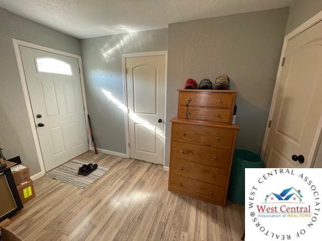 412 E Walnut St, Clinton, MO 64735 - entrance foyer with light wood-style floors, a textured ceiling, and baseboards