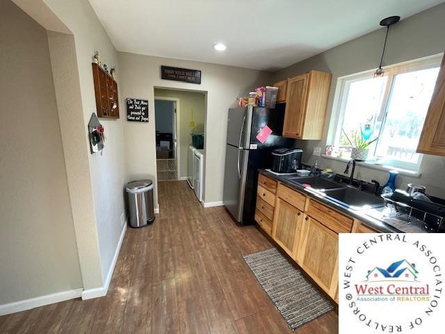 412 E Walnut St, Clinton, MO 64735 - kitchen featuring a sink, dark countertops, dark wood-style floors, freestanding refrigerator, and washer and clothes dryer