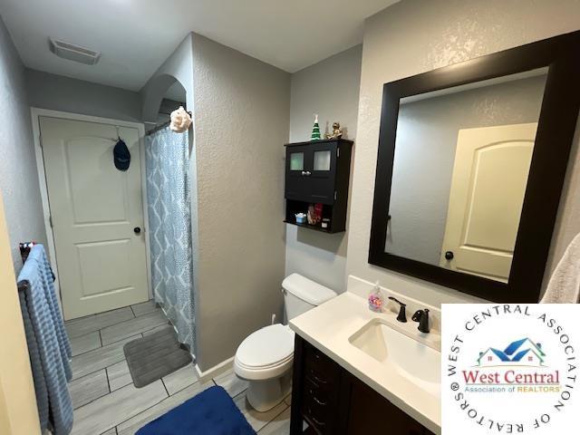 412 E Walnut St, Clinton, MO 64735 - full bathroom with toilet, vanity, a textured wall, and a shower with curtain