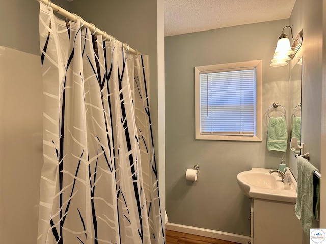 full bath with vanity, curtained shower, baseboards, a textured ceiling, and wood finished floors