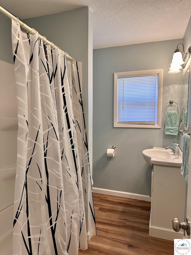 full bath featuring a shower with shower curtain, vanity, wood finished floors, and baseboards