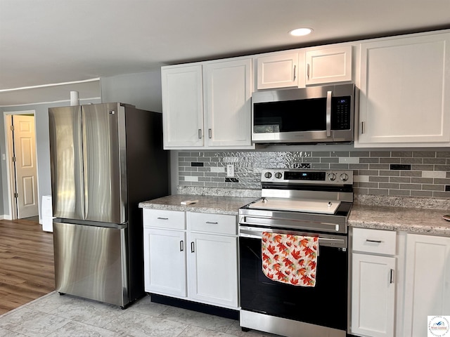 kitchen featuring white cabinetry, stainless steel appliances, and backsplash