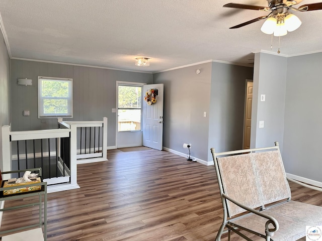 entryway with baseboards, ornamental molding, a textured ceiling, and wood finished floors