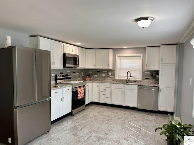 kitchen featuring appliances with stainless steel finishes, white cabinetry, decorative backsplash, and a sink