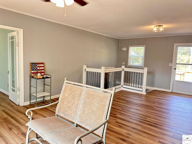 sitting room featuring ornamental molding, a textured ceiling, and wood finished floors