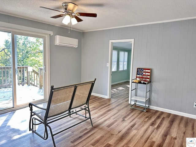 dining area featuring a wall unit AC, a ceiling fan, ornamental molding, a textured ceiling, and wood finished floors