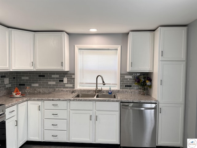 kitchen featuring stainless steel dishwasher, a sink, white cabinets, and decorative backsplash