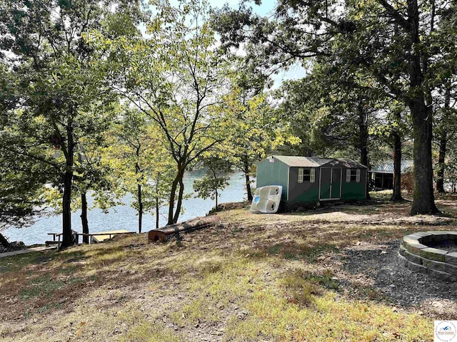 view of yard featuring a storage shed, a water view, and an outbuilding