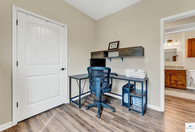 office featuring a sink, wood finished floors, and baseboards