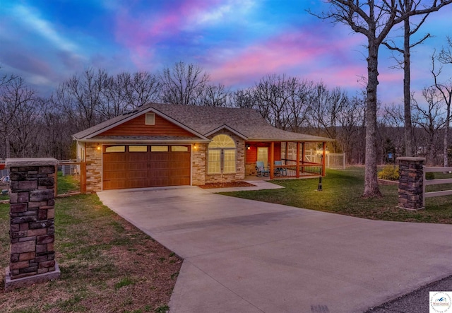 view of front of property with a porch, fence, a lawn, driveway, and an attached garage
