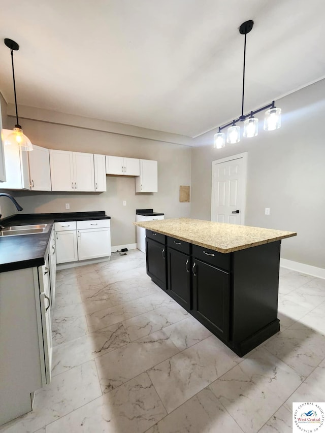 kitchen featuring dark cabinets, a kitchen island, marble finish floor, a sink, and baseboards