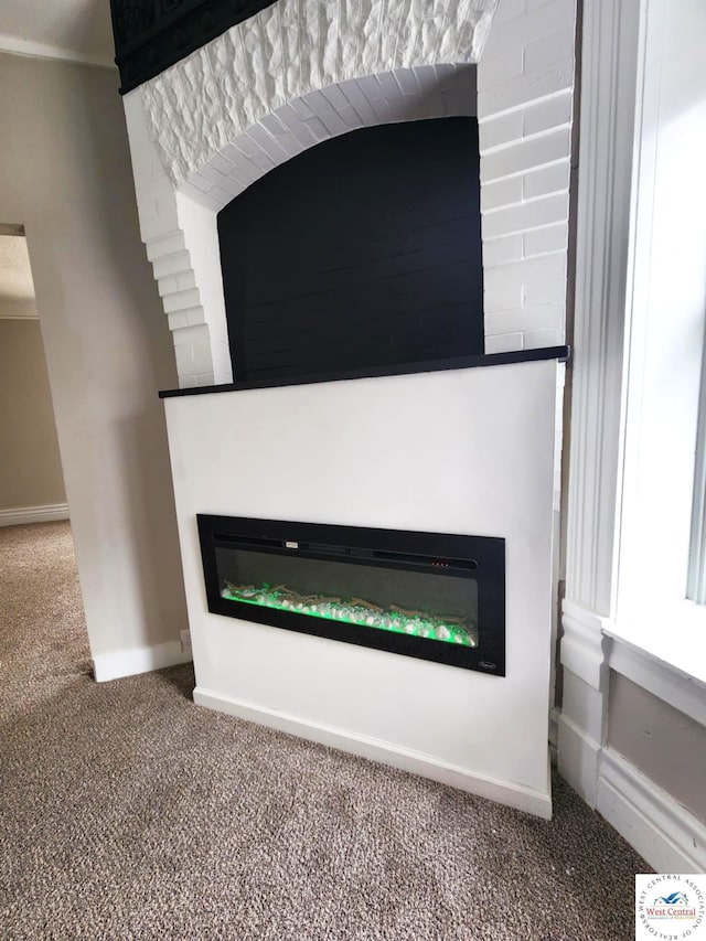 interior details with a glass covered fireplace, baseboards, and carpet floors