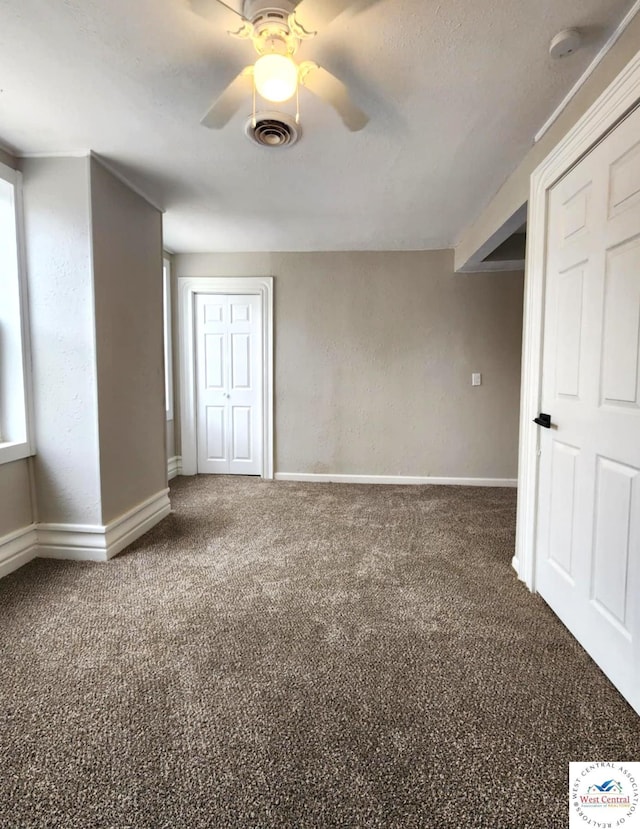 unfurnished room with visible vents, ceiling fan, carpet, and baseboards