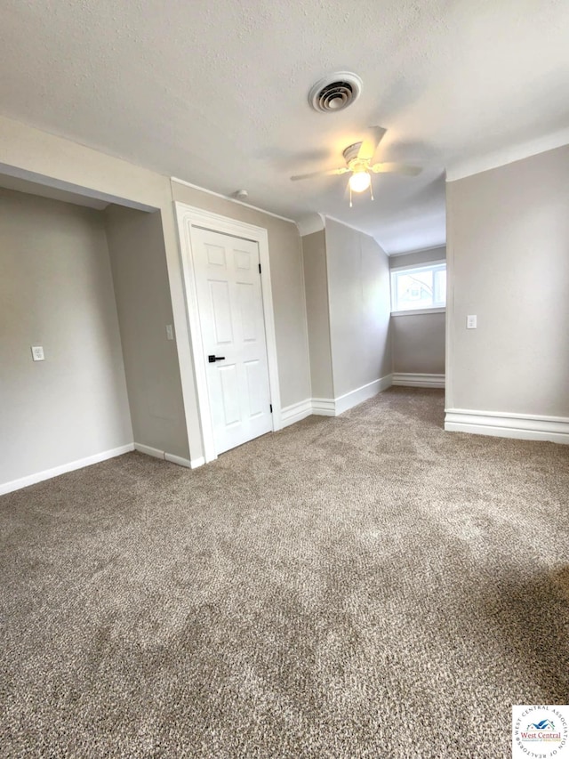 spare room with a ceiling fan, visible vents, carpet floors, and baseboards