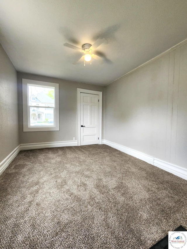 carpeted spare room featuring baseboards and a ceiling fan