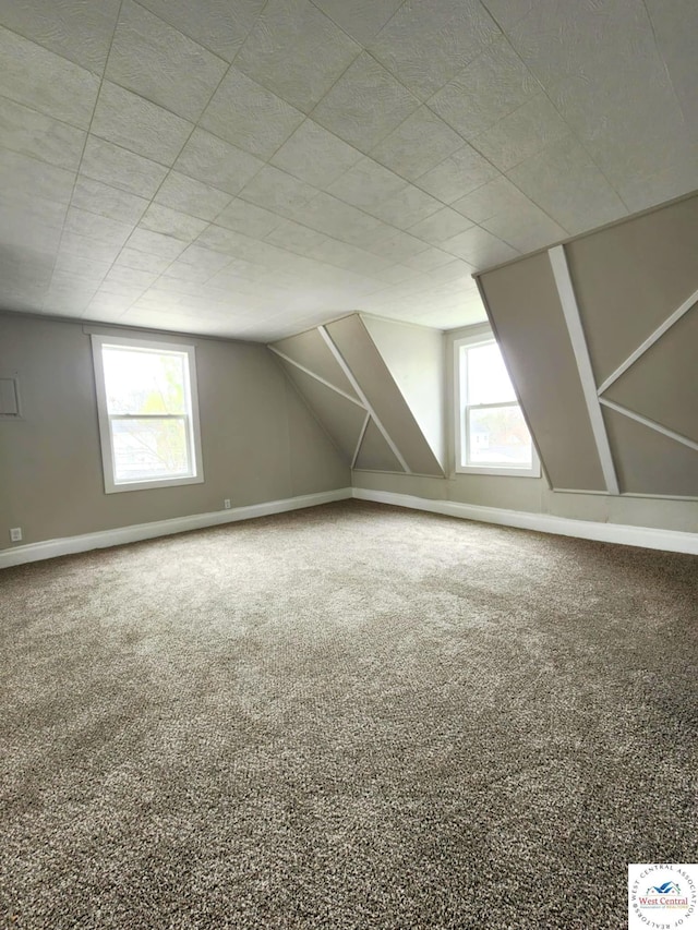 bonus room with vaulted ceiling, carpet floors, and baseboards