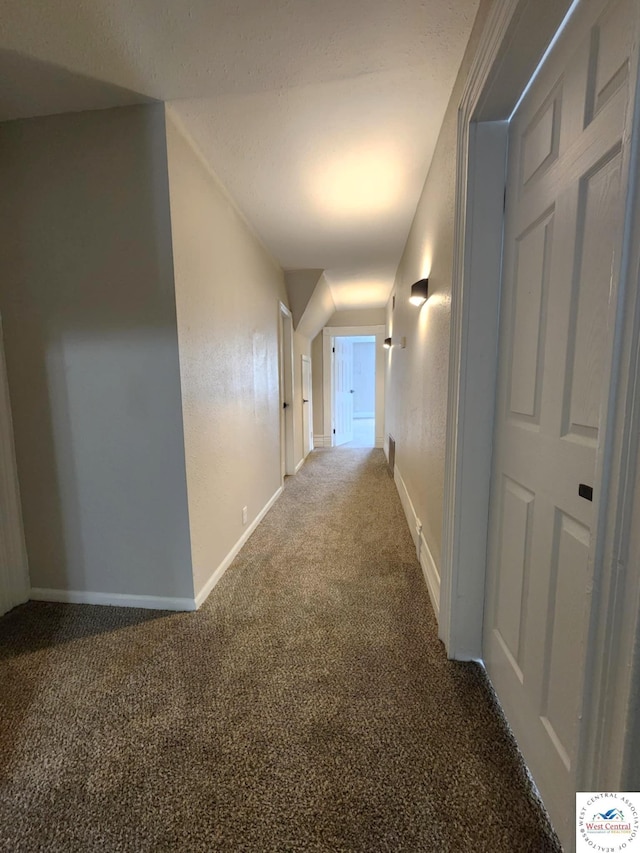 hallway featuring baseboards and carpet