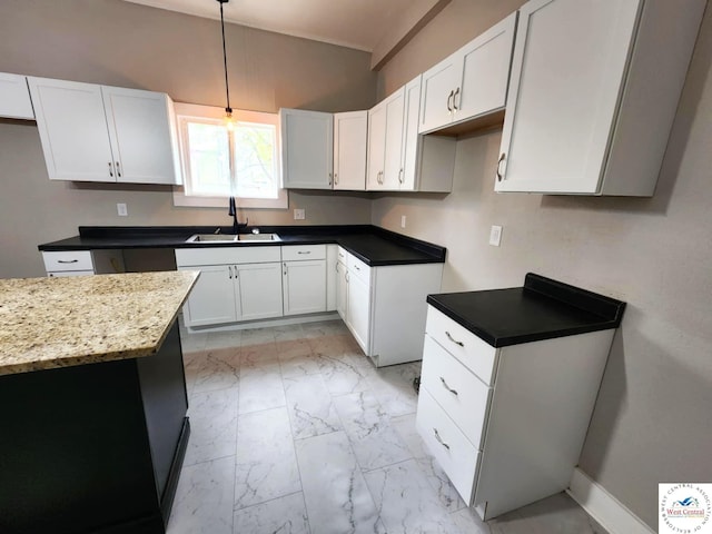 kitchen with a sink, marble finish floor, baseboards, pendant lighting, and white cabinets