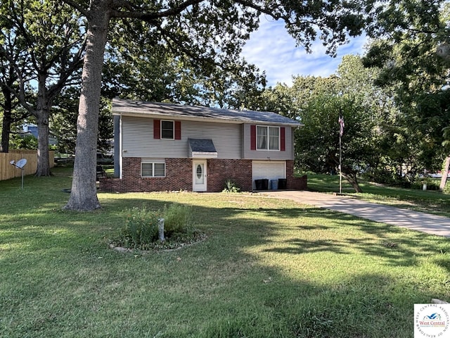 bi-level home featuring a garage, brick siding, a front yard, and concrete driveway