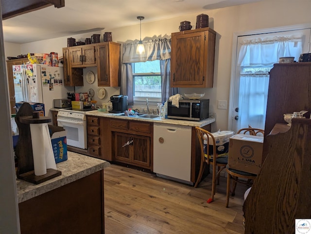 418 W Gravel St, Clinton, MO 64735 - kitchen featuring white appliances, light wood-style flooring, decorative light fixtures, light countertops, and a sink