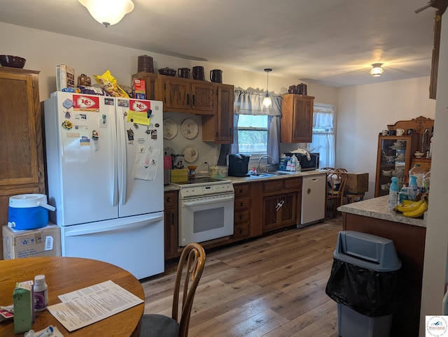 418 W Gravel St, Clinton, MO 64735 - kitchen featuring a sink, wood-type flooring, white appliances, decorative light fixtures, and light countertops