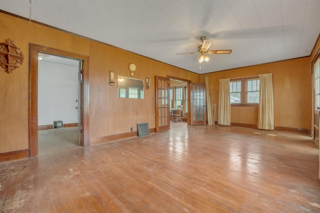 245 Randolph St, Tipton, MO 65081 - unfurnished living room featuring wooden walls, ceiling fan, wood finished floors, and baseboards